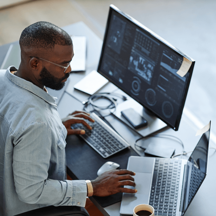 Man looking at laptop and monitor screen