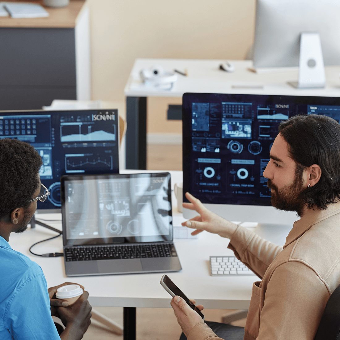Two men looking at computer screens and talking