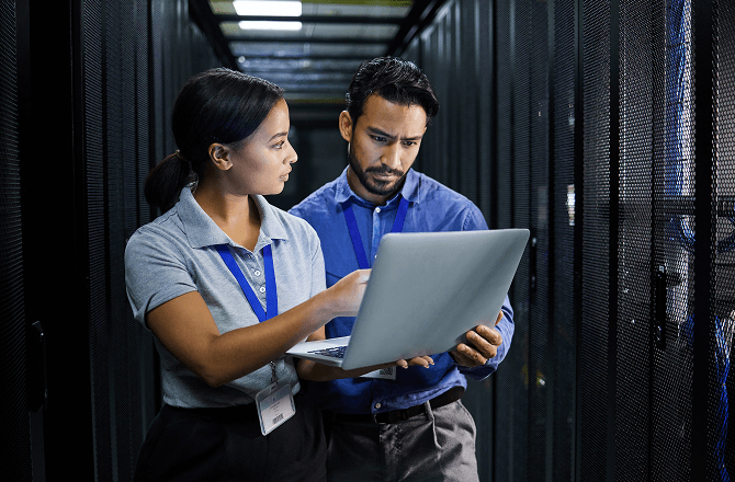 Woman and man looking at a laptop in server room